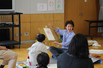 触覚で描いた男の子の手を見せる水野さん